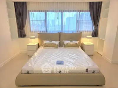 Spacious bedroom with large windows and modern furnishings in a high-rise apartment.