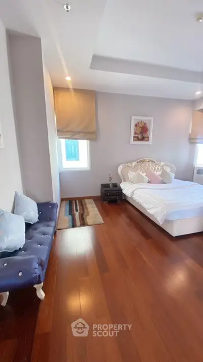 Elegant bedroom with hardwood floors and stylish decor, featuring a cozy bed and chic seating area.