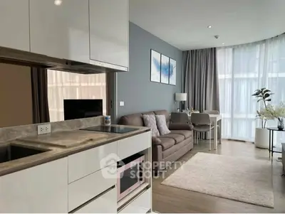 Modern open-plan living room with sleek kitchen and cozy seating area, featuring large windows and stylish decor.