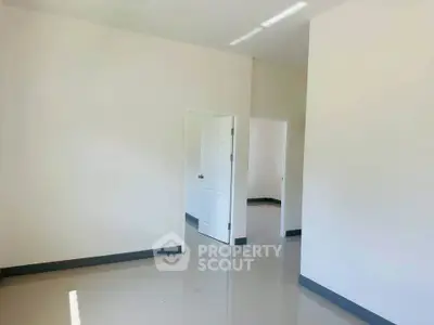 Spacious empty room with glossy floors and white walls, ready for customization.