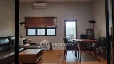Modern living room with stylish furniture and wooden flooring, featuring a cozy seating area and dining table.