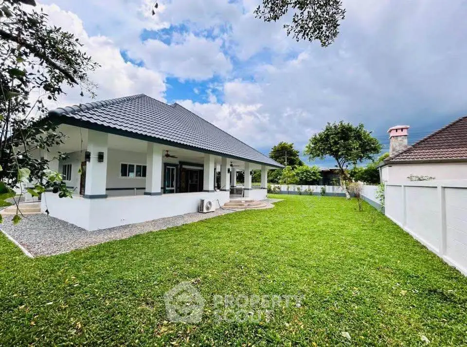 Charming single-story home with spacious green lawn and modern roof design.
