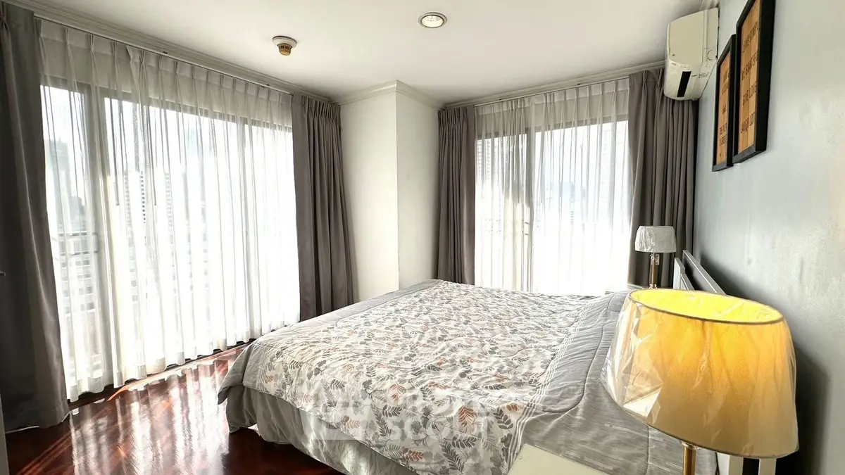 Bright and airy bedroom with large windows and elegant decor in a modern apartment.