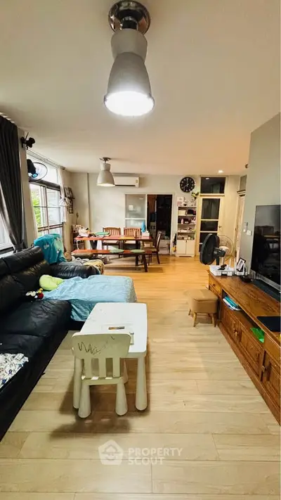 Spacious living room with modern decor and natural light, featuring a cozy seating area and dining space.