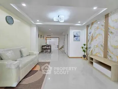 Spacious modern living room with elegant decor and marble accent wall.