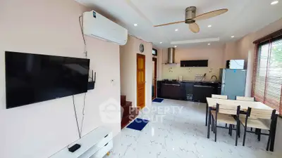 Modern open-plan living room with kitchen, featuring sleek furniture and appliances.