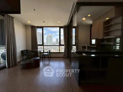 Spacious living room with city view and modern kitchen in high-rise apartment.