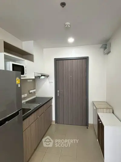 Modern compact kitchen with sleek cabinetry and stainless steel appliances in a cozy apartment.