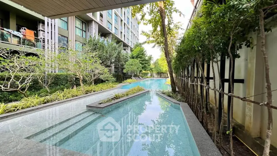 Luxurious apartment complex with serene pool and lush greenery, perfect for relaxation and modern living.