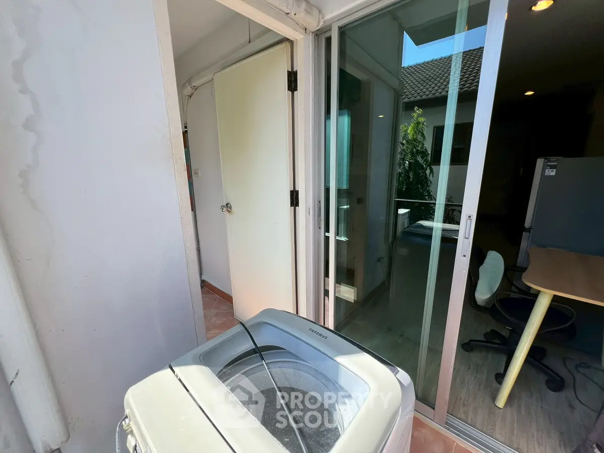 Charming balcony with washing machine and sliding glass doors, perfect for convenient laundry access.