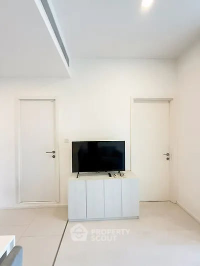 Modern minimalist living room with sleek TV stand and white doors