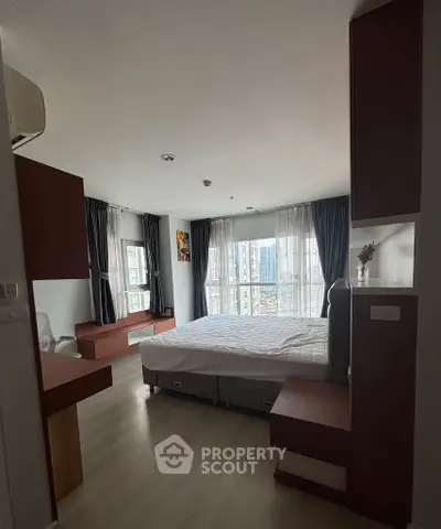 Spacious bedroom with large windows and modern furnishings in a high-rise apartment.