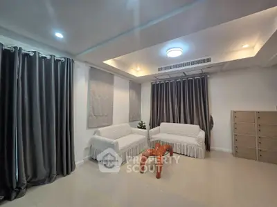 Spacious living room with modern ceiling lights and elegant curtains, featuring cozy sofas and a unique wooden coffee table.