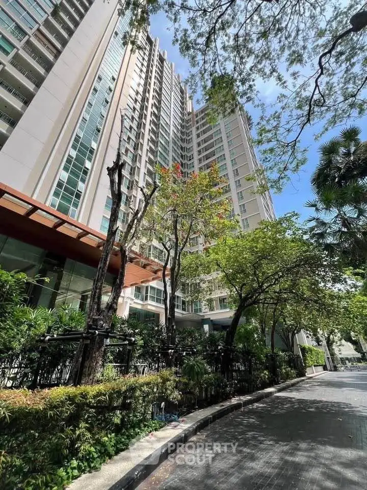 Modern high-rise building with lush greenery and clear blue sky