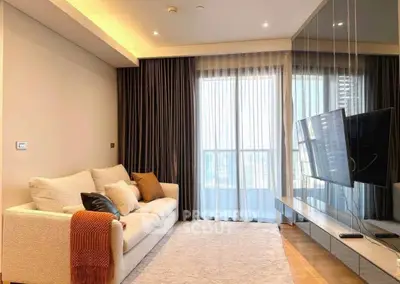 Modern living room with cozy sofa and wall-mounted TV, featuring floor-to-ceiling windows and elegant curtains.