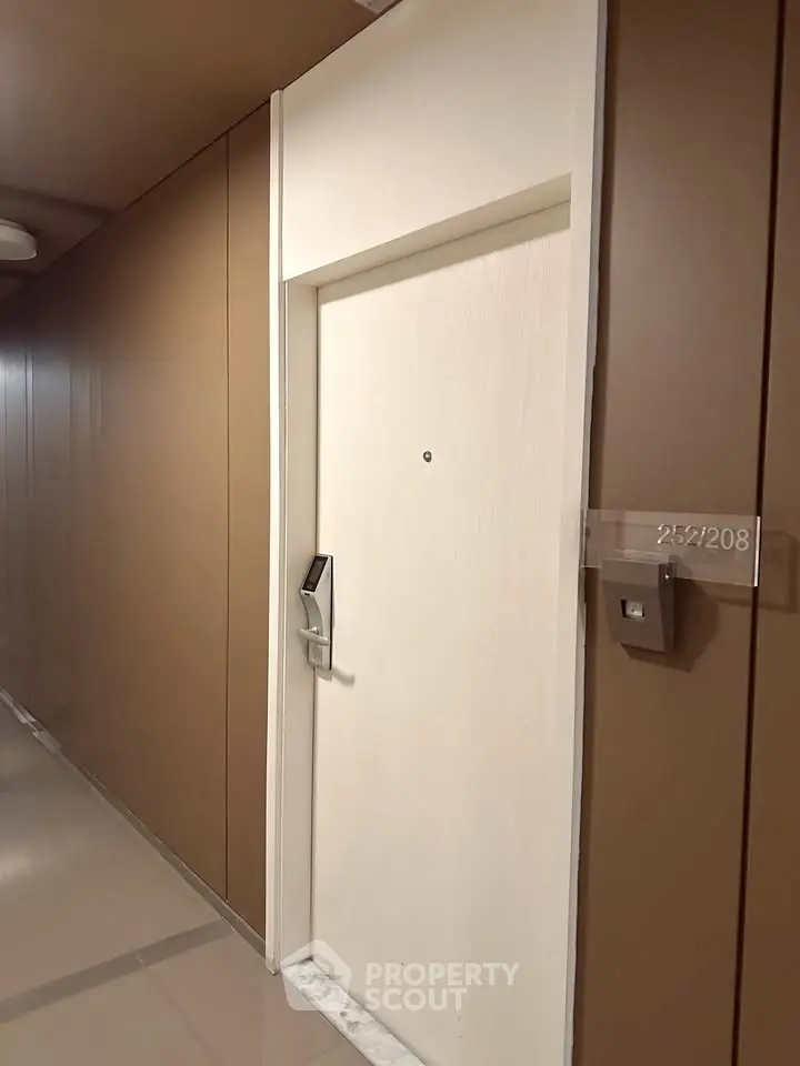 Modern apartment entrance with sleek door and electronic lock in a stylish hallway.