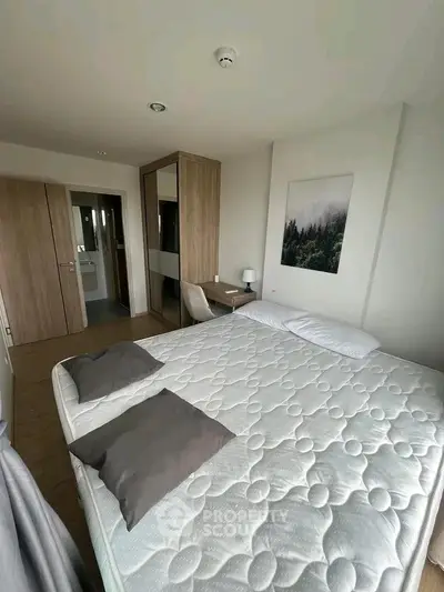 Cozy bedroom with modern decor and ample natural light, featuring a comfortable bed and stylish wooden furniture.