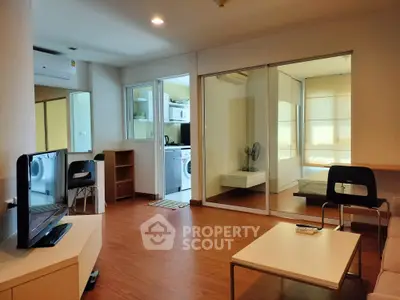 Modern living room with wooden flooring and glass partition to bedroom