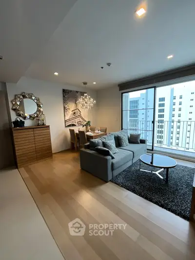 Modern living room with stylish decor and city view balcony in a high-rise apartment.