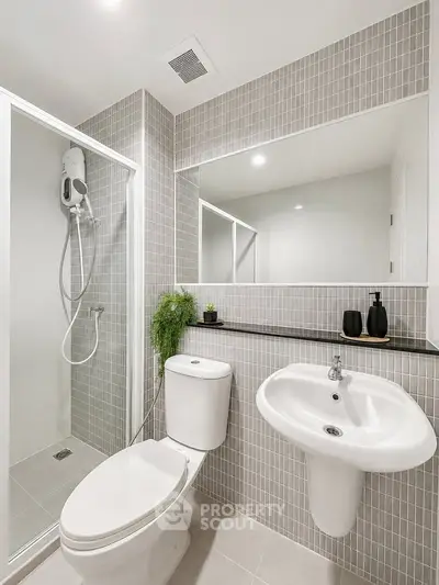 Modern bathroom with sleek design, featuring a shower, toilet, and stylish sink in a contemporary setting.