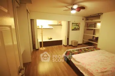 Spacious bedroom with modern decor and wooden flooring, featuring a ceiling fan and cozy ambiance.