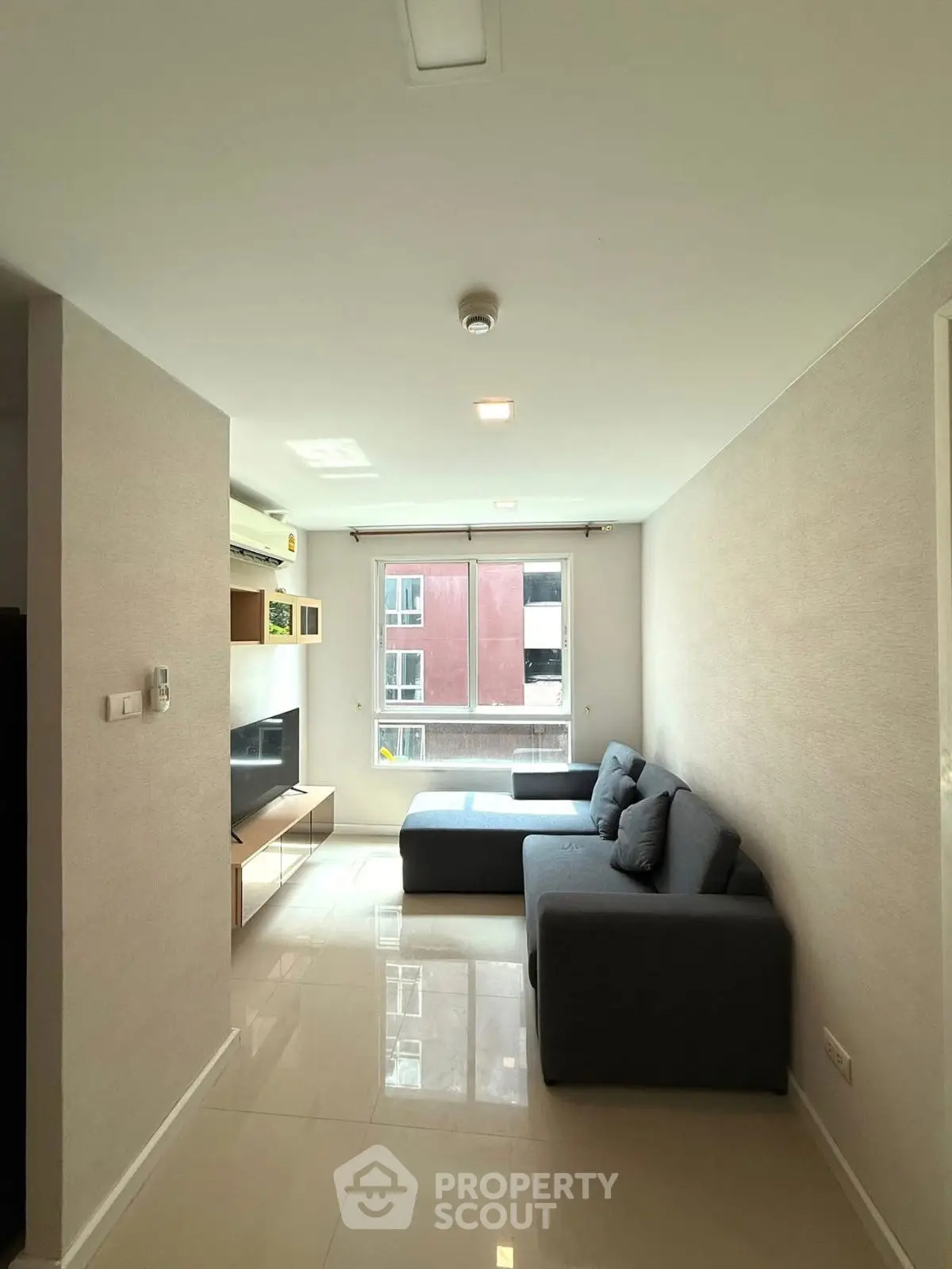 Modern living room with sleek furniture and large window offering natural light.