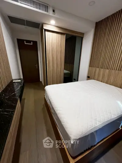 Modern bedroom with wooden accents and sleek design, featuring a comfortable bed and stylish decor.