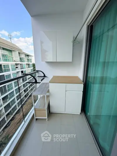 Modern balcony with sleek cabinetry and glass railing offering a view of nearby buildings.