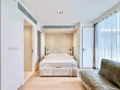 Modern bedroom with natural light, featuring a cozy bed and sleek design elements.