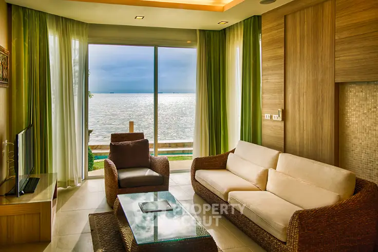 Luxurious living room with stunning ocean view, elegant wicker furniture, and floor-to-ceiling windows.