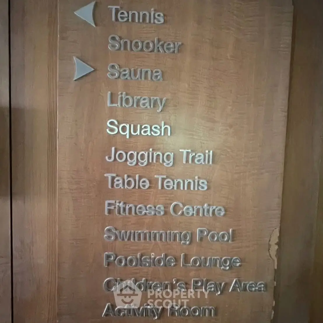 Wooden sign listing amenities like tennis, snooker, sauna, library, squash, jogging trail, and more.
