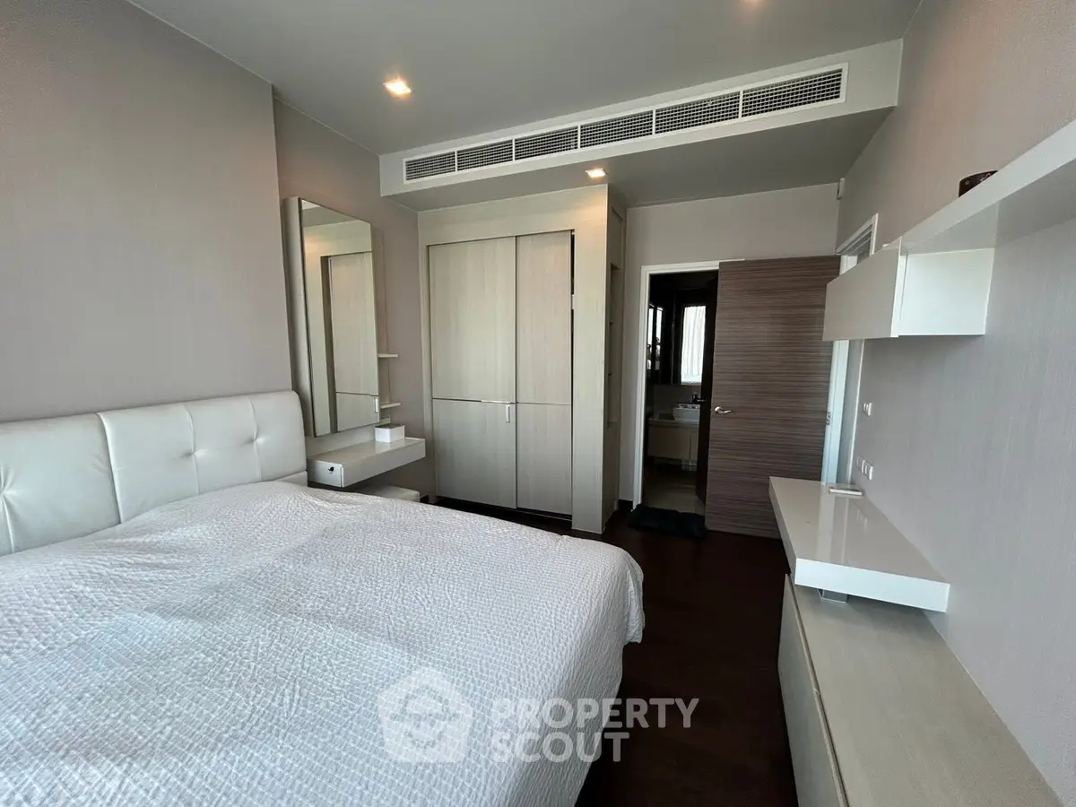 Modern bedroom with sleek design, featuring built-in wardrobe and elegant white furnishings.