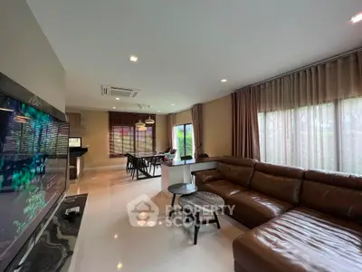Spacious modern living room with leather sofa and large windows offering natural light