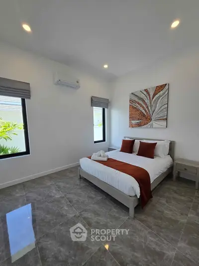 Modern bedroom with stylish decor and natural light, featuring a comfortable bed and elegant artwork.