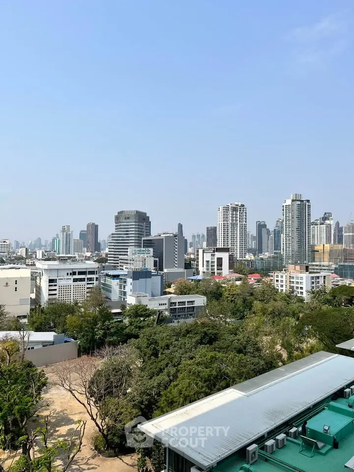 Stunning cityscape view from a high-rise building showcasing urban skyline and lush greenery.