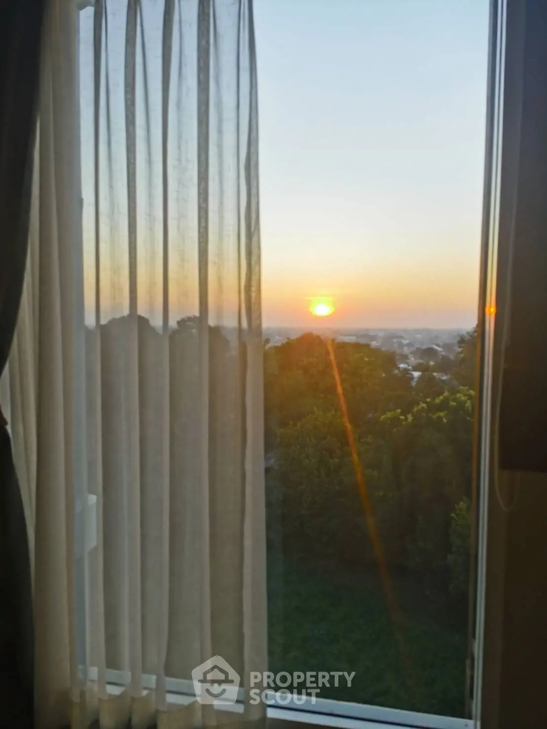 Stunning sunset view from a cozy window with sheer curtains