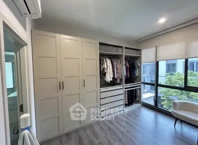 Spacious bedroom with modern wardrobe and large window offering natural light and scenic view.