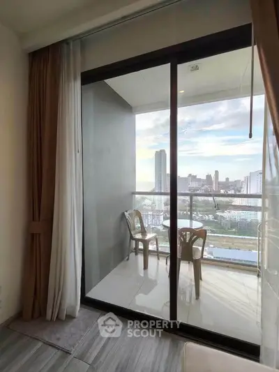 Modern apartment balcony with stunning city view and cozy seating area.