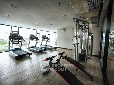 Modern gym with state-of-the-art equipment and large windows offering city views.