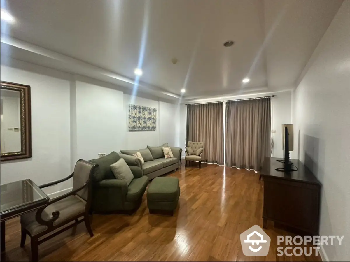 Spacious living room with polished hardwood floors, modern furniture, and ample natural light, perfect for entertaining guests or relaxing.