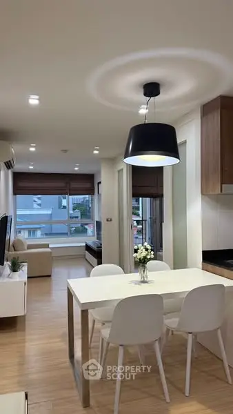 Modern open-plan living and dining area with stylish lighting and wooden flooring.