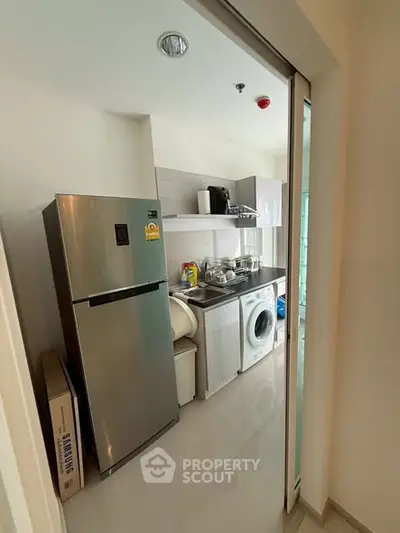 Modern kitchen with stainless steel fridge and washing machine in compact layout.