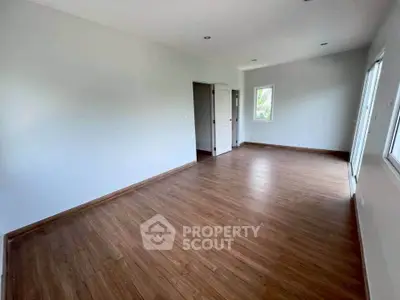 Spacious empty room with wooden flooring and natural light, perfect for customization.