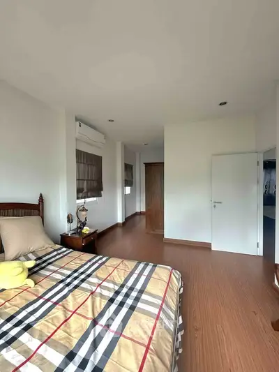 Spacious bedroom with wooden flooring and modern decor in a bright, airy apartment.