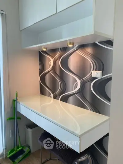 Modern study nook with sleek white desk and stylish wallpaper, perfect for compact spaces.