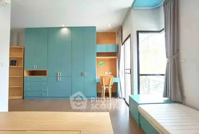 Modern bedroom with built-in blue wardrobes and study area, featuring large windows for natural light.