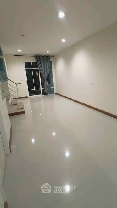 Spacious empty living room with glossy tile flooring and sliding glass doors.