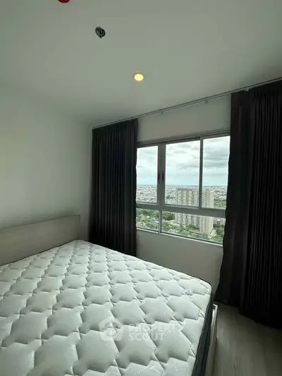 Cozy bedroom with large window offering stunning city views, perfect for urban living.