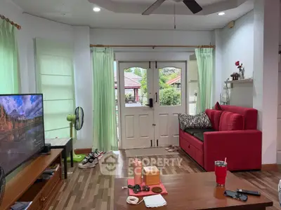 Cozy living room with red sofa and large windows overlooking garden