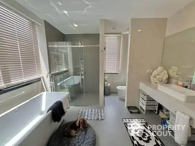 Luxurious modern bathroom with bathtub and glass shower enclosure, featuring elegant decor and ample natural light.